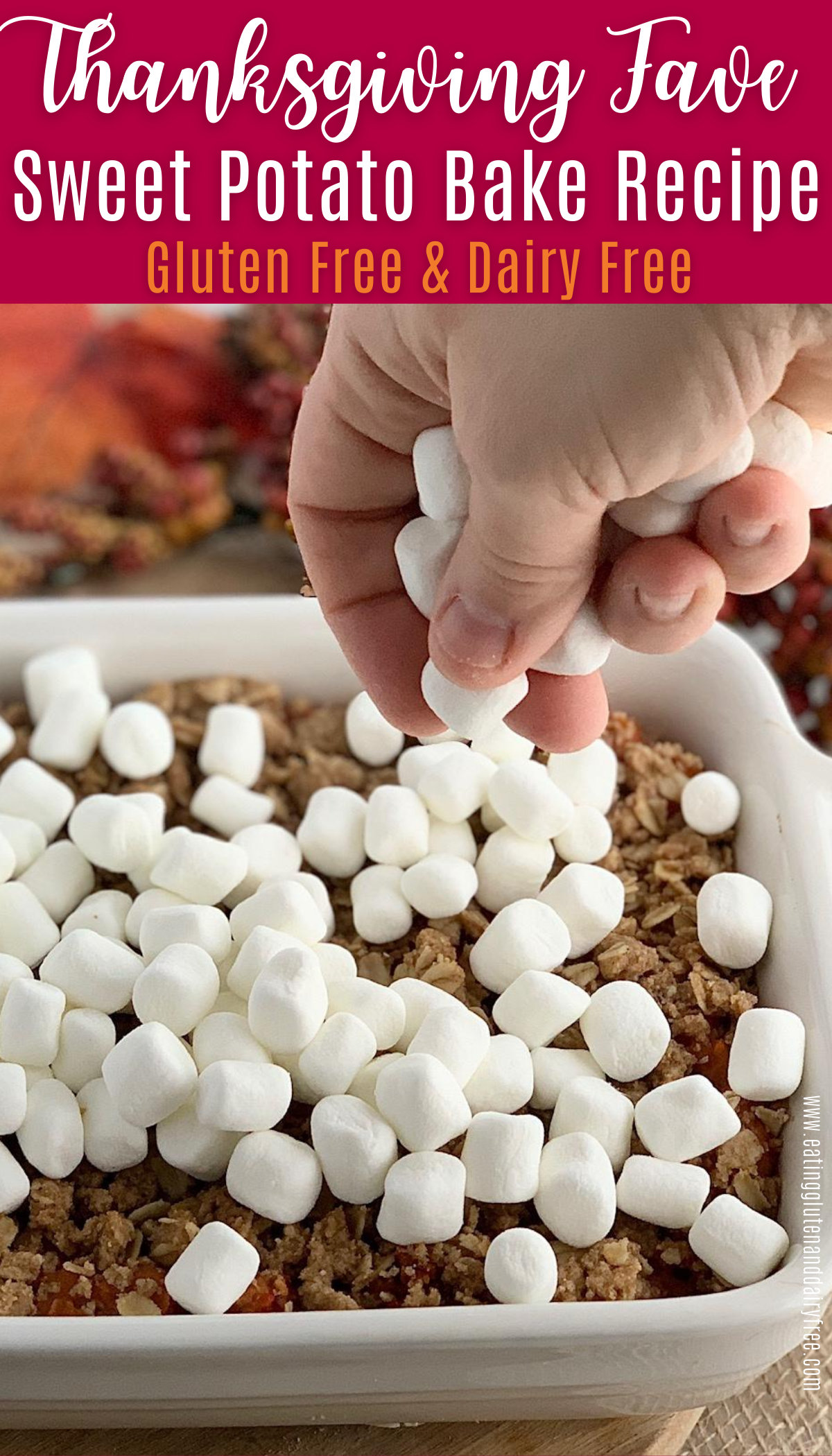 A hand dropping marshmallows on top of a sweet potato bake dish.