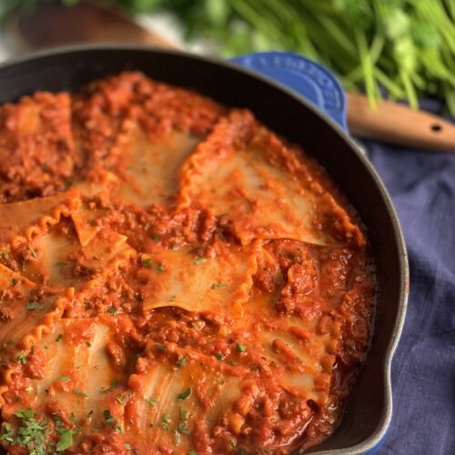 A skillet filled with tender lasagn noodles broken into pieces in a meaty marinara sauce.