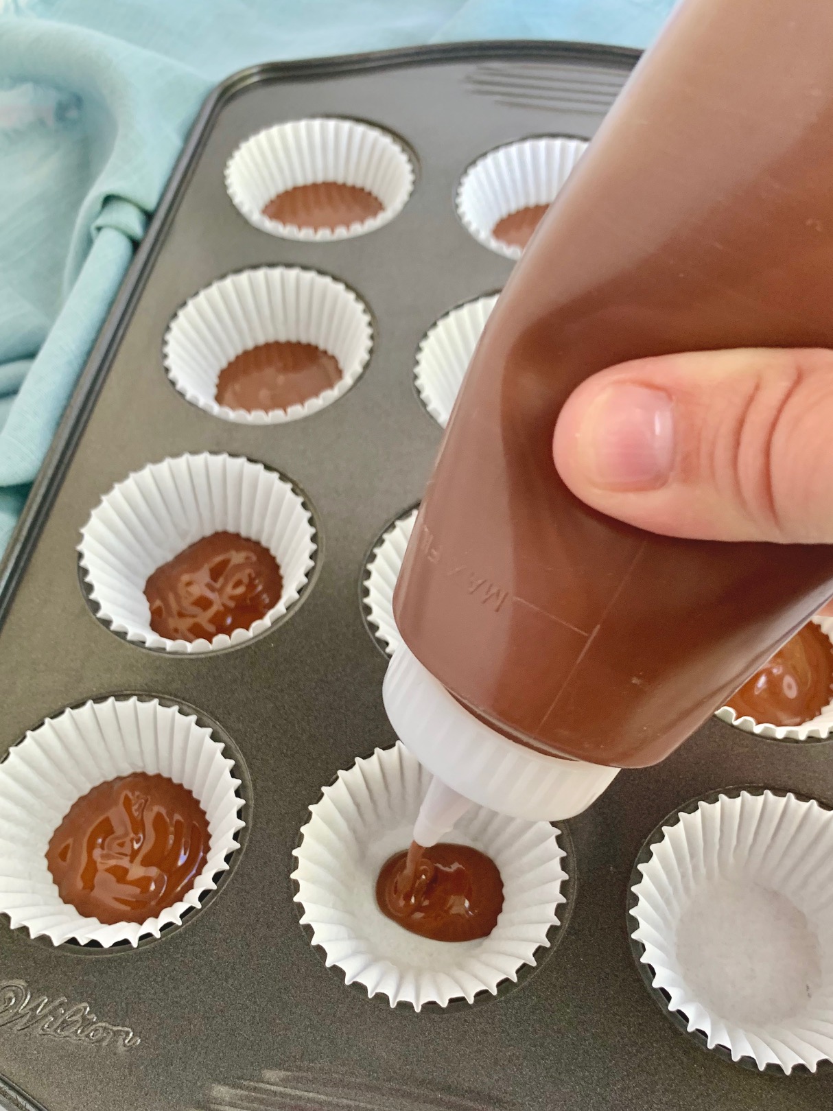 Filling a mini muffin pan with a layer of melted chocoalte