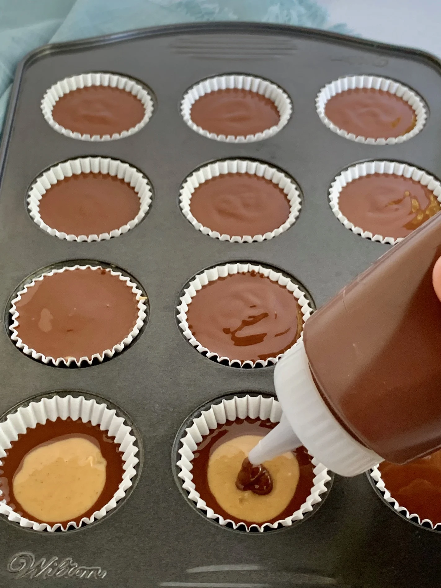 Place the top layer of melted chocolate on the peanut butter cups