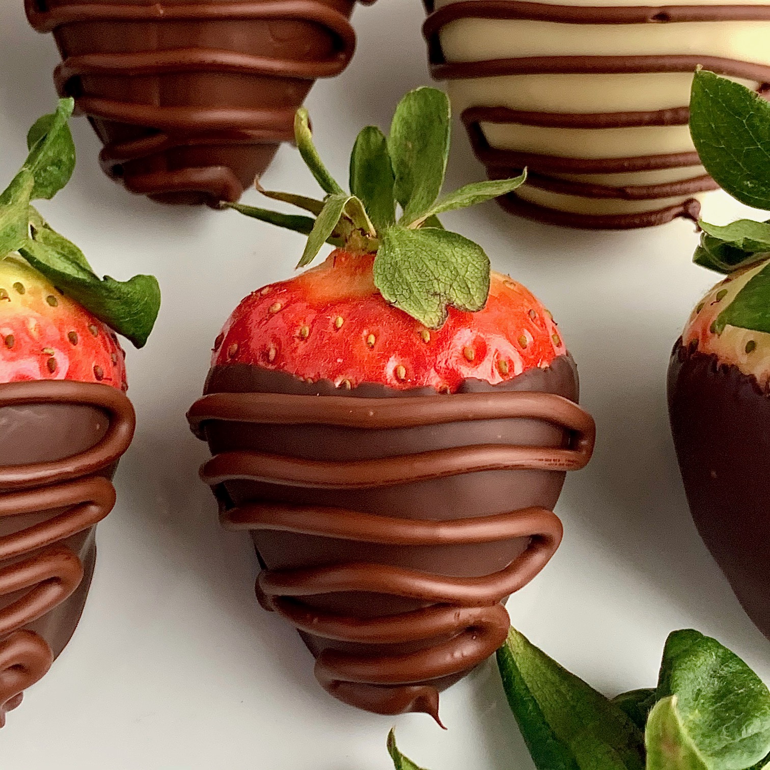 A strawberry with melted chocolate drizzled across it.