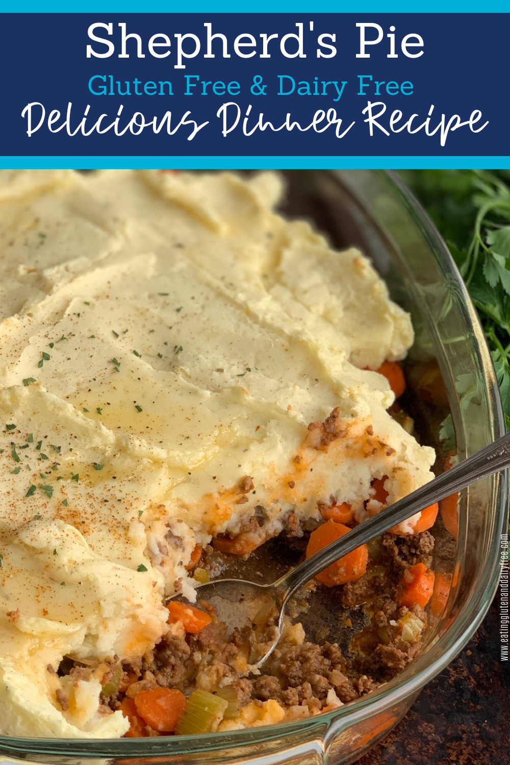 A 9x13-inch glass baking pan with a seasoned ground beef, carrot, and celery mixture topped with creamy, thick mashed potatoes. You'll see melted dairy free butter and little pieces of fresh parsley on top of the mashed potatoes. A spoon has scooped out a portion of the shepherd's pie.. 