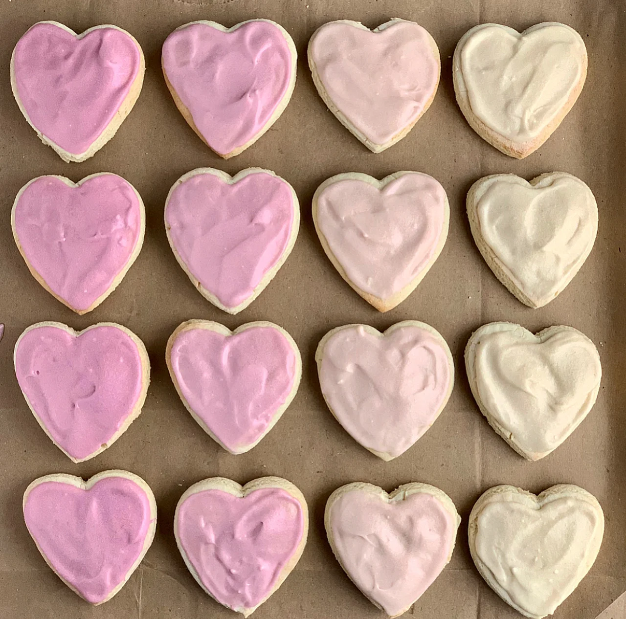 Several heart-shaped sugar cookies iced with an ombre coloring of pink to very light pink