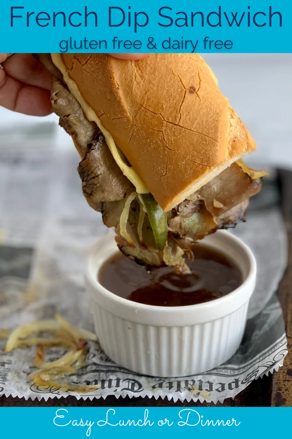 A sliced baguette with saut&Atilde;&copy;ed onions and green peppers and roast beef being dipped into a Au Jus.