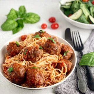 A bowl of Homemade Italian Meatballs that are gluten free, dairy free and sitting with a bowl of pasta.