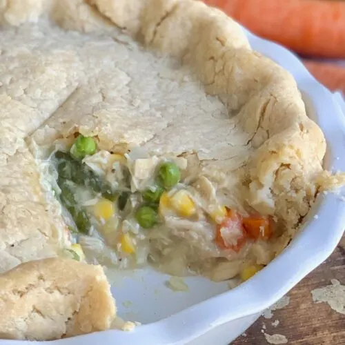 A filling of several different vegetables tucked in a buttery crust in a white pie plate.