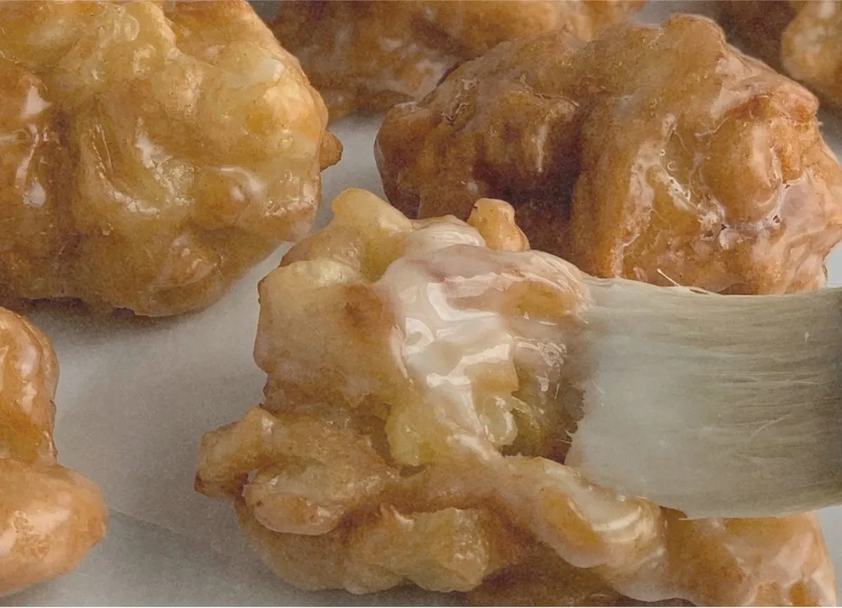A pastry brush brushing please on fresh me gluten-free apple fritters.