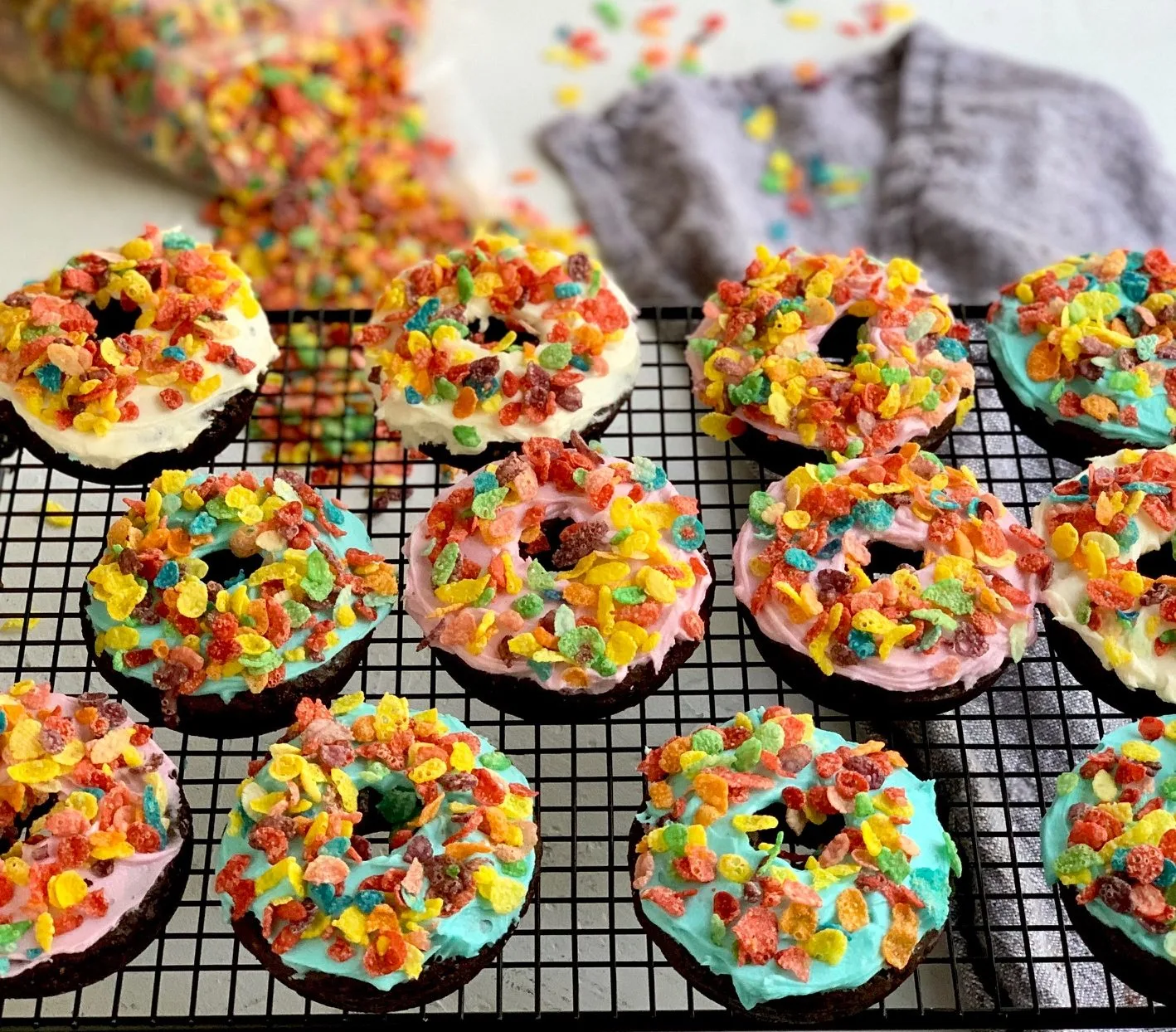 chocolate donuts with frosting and fruity pebble cereal on top