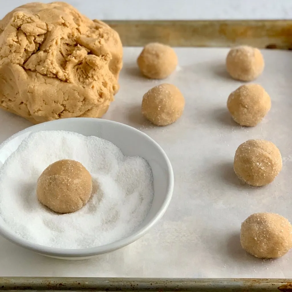 A baking sheet with peanut butter cookies shaped in a ball an dipped in sugar before they go in the oven