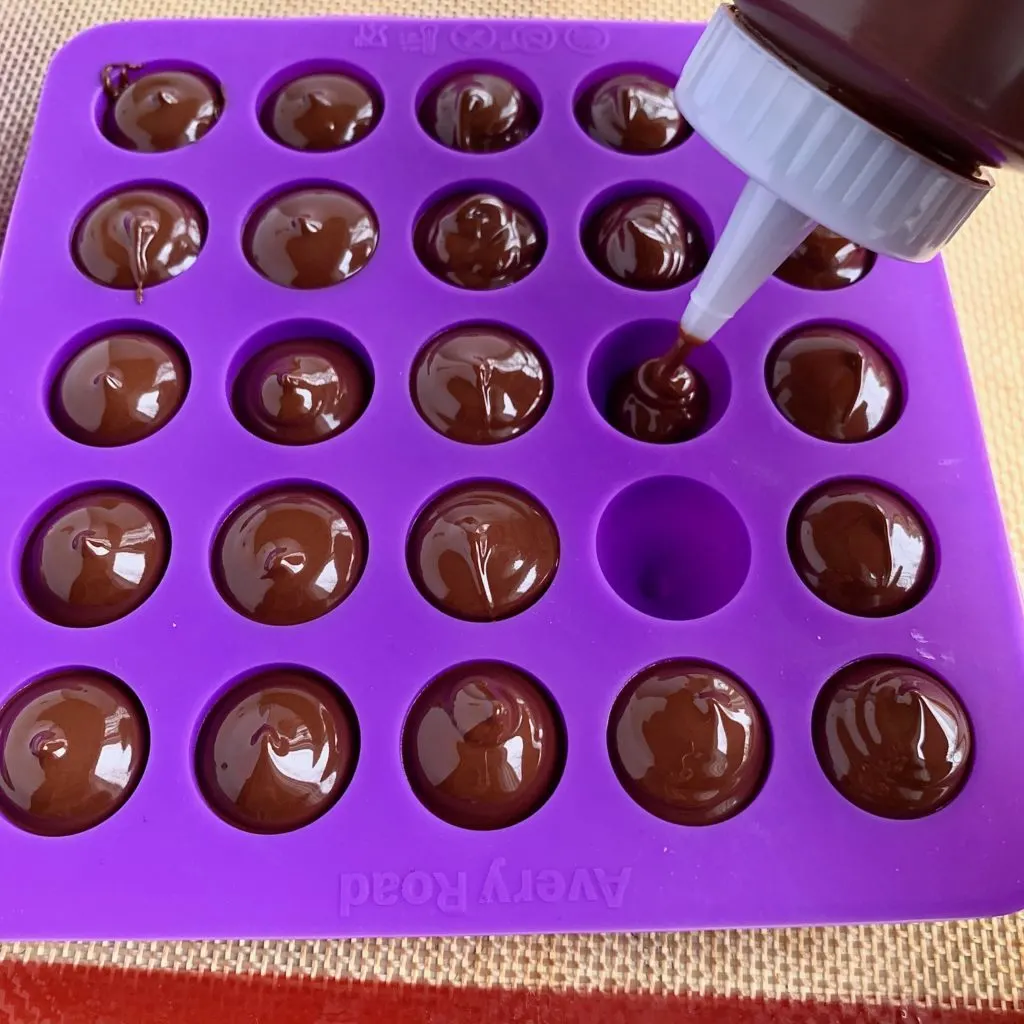 filling up a kiss mold with melted chocolate