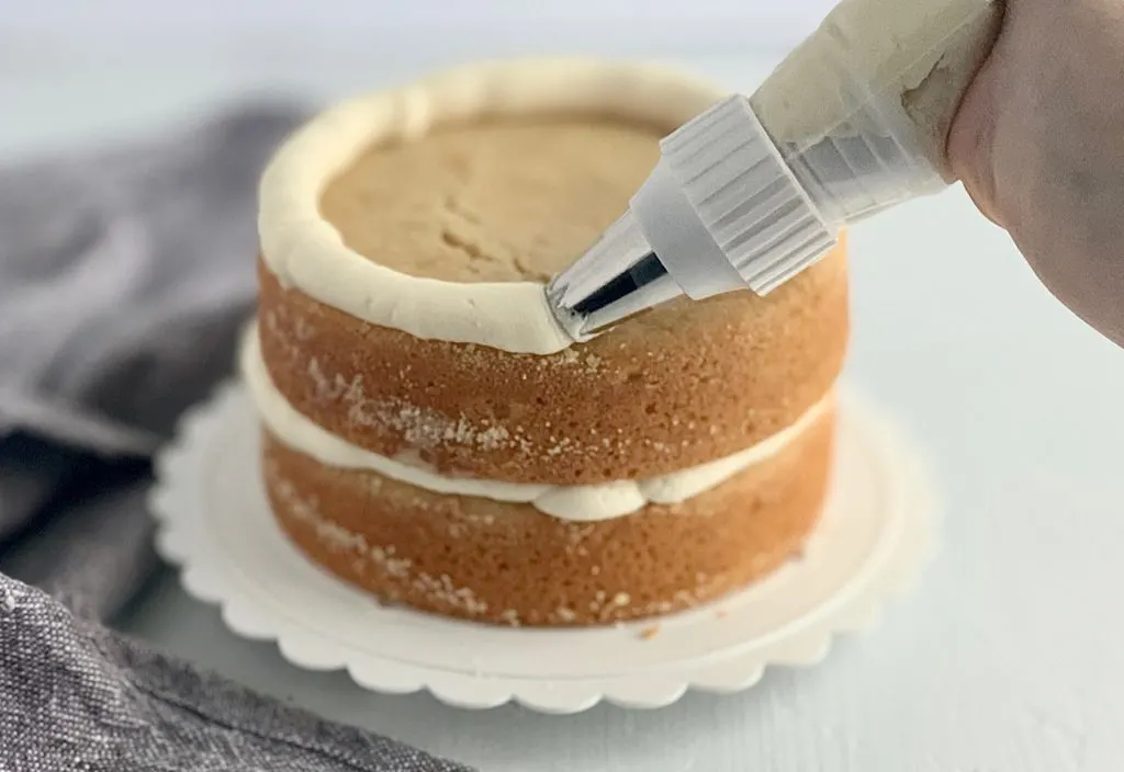 piping icing onto vanilla cakes