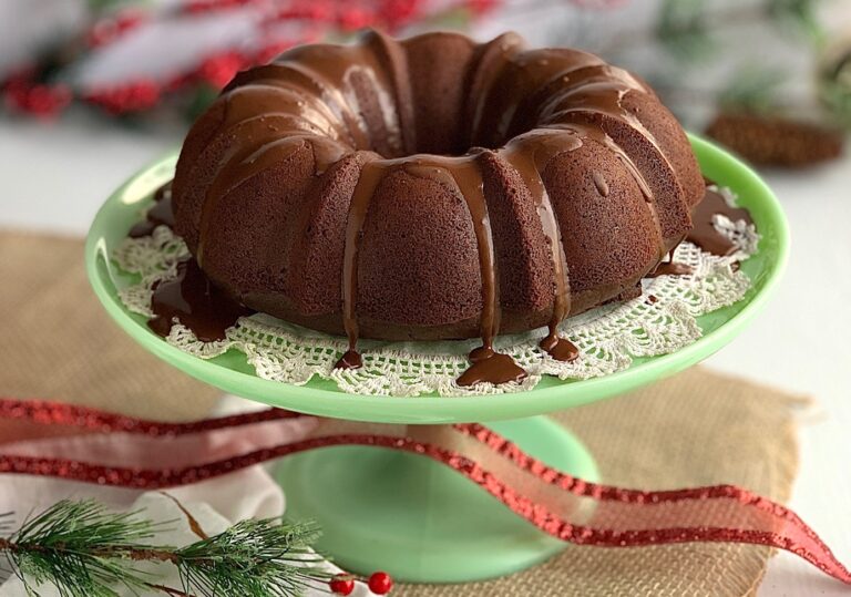 A chocolate bundt cake with chocolate ganache on a green platter.