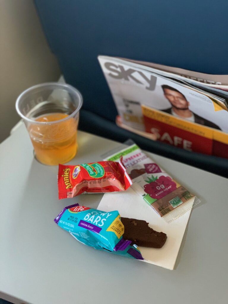snacks and a drink on an airplane tray table