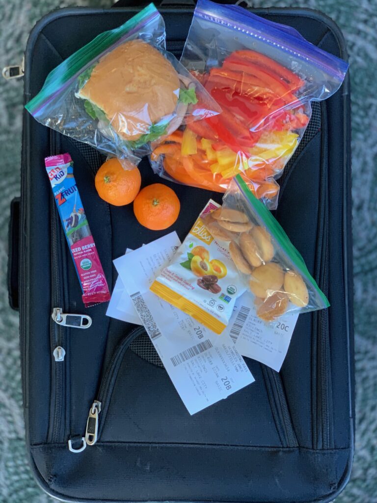 several snacks items on top of a carry on bag