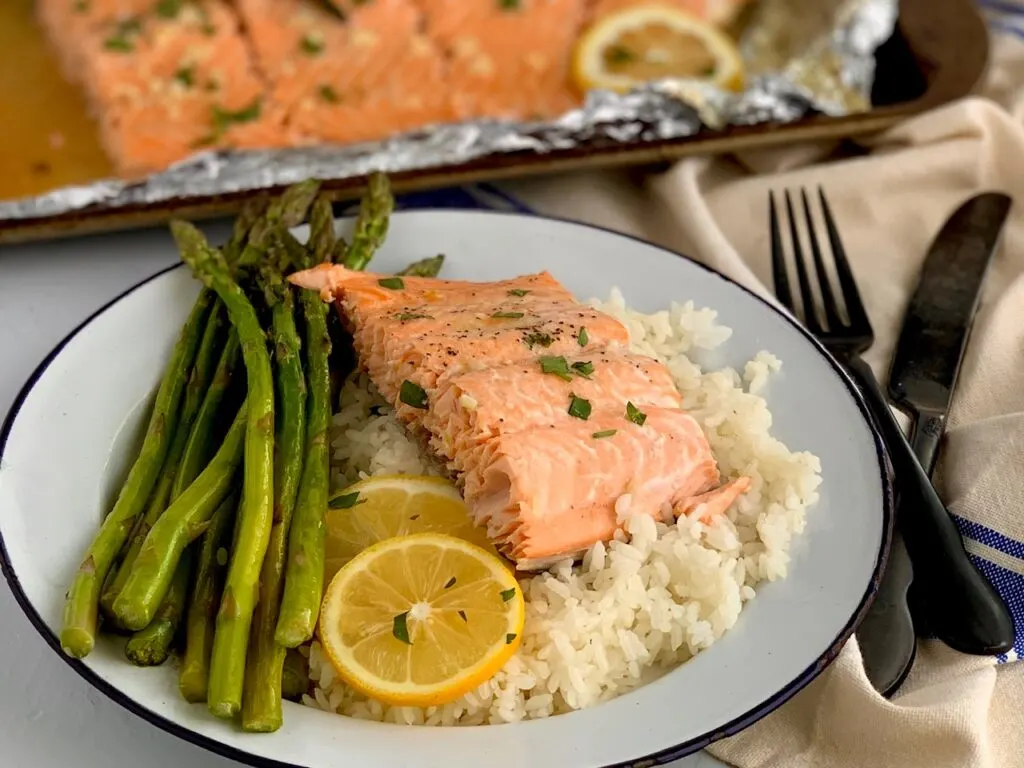 Flaky salmon on a bed of white rice with a side of asparagus.