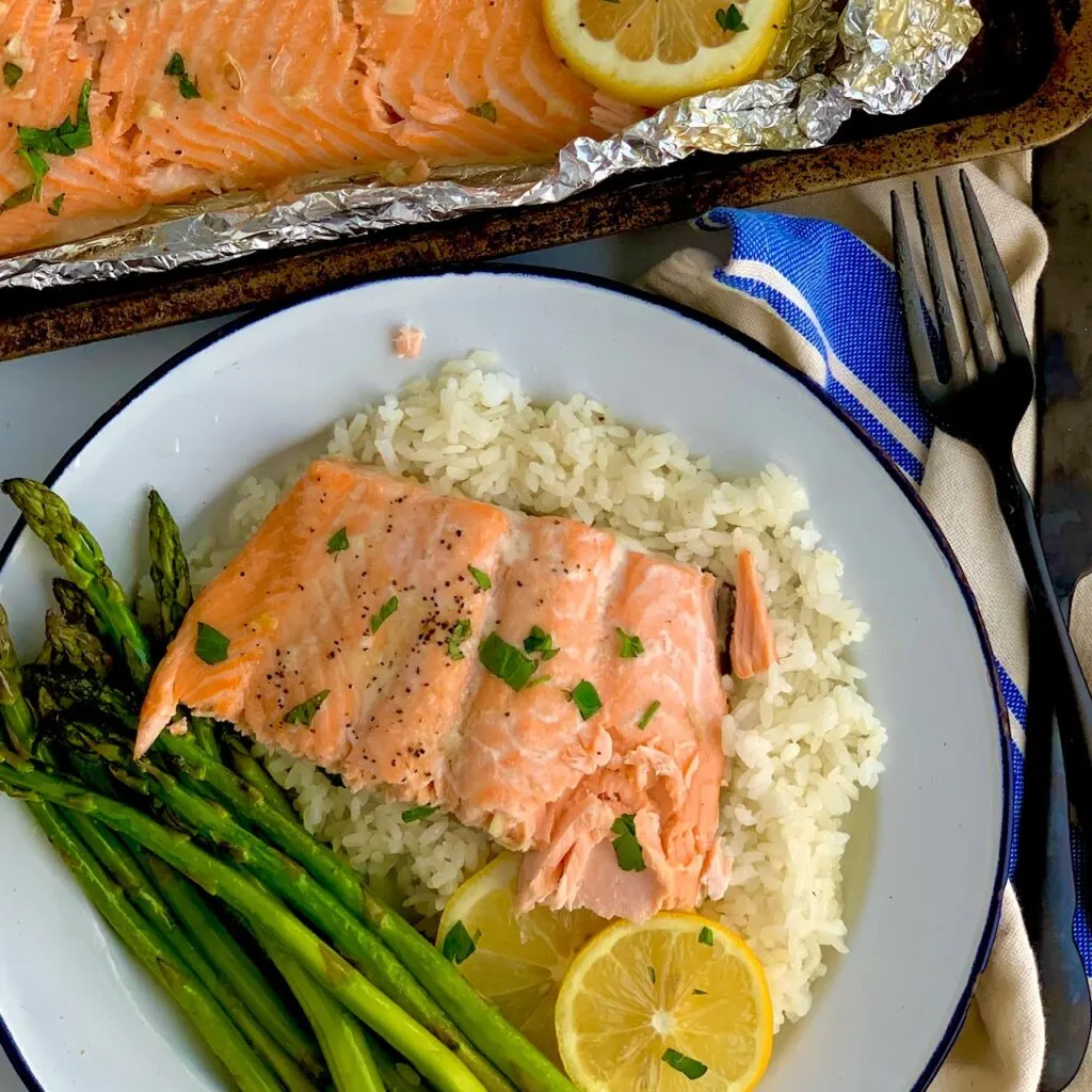 Flaky salmon on a bed of white rice and a side of asparagus.