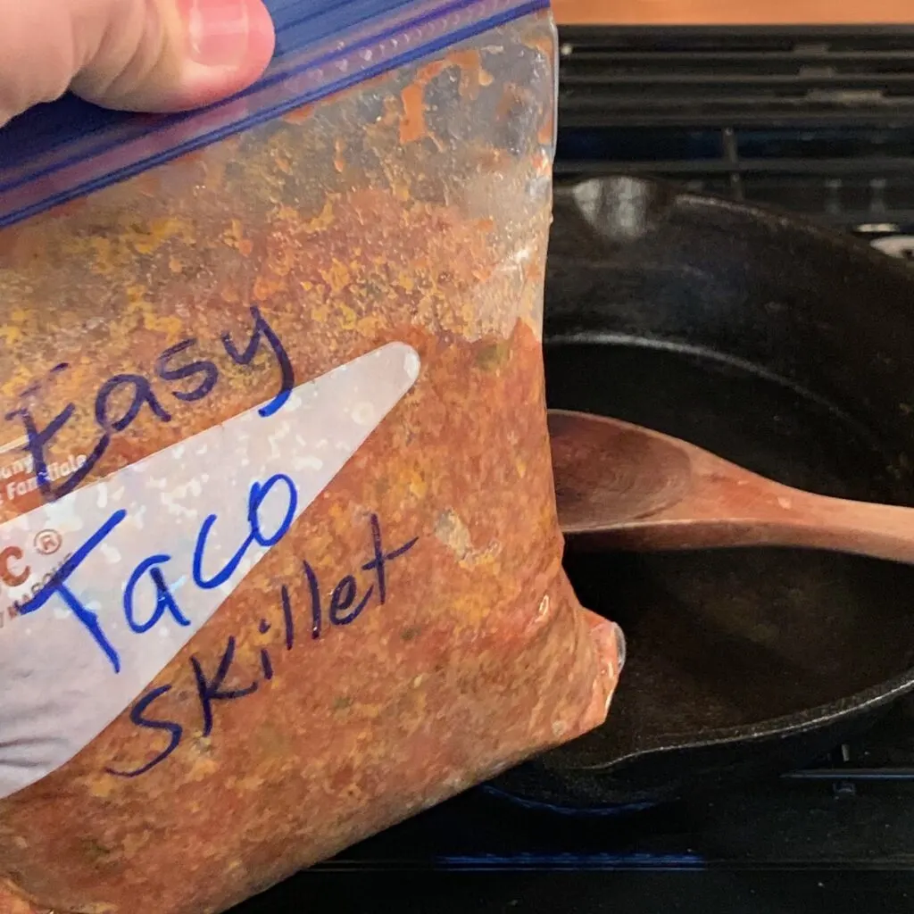 A Ziploc bag full of pre made Easy Taco Skillet ingredients over a skillet.