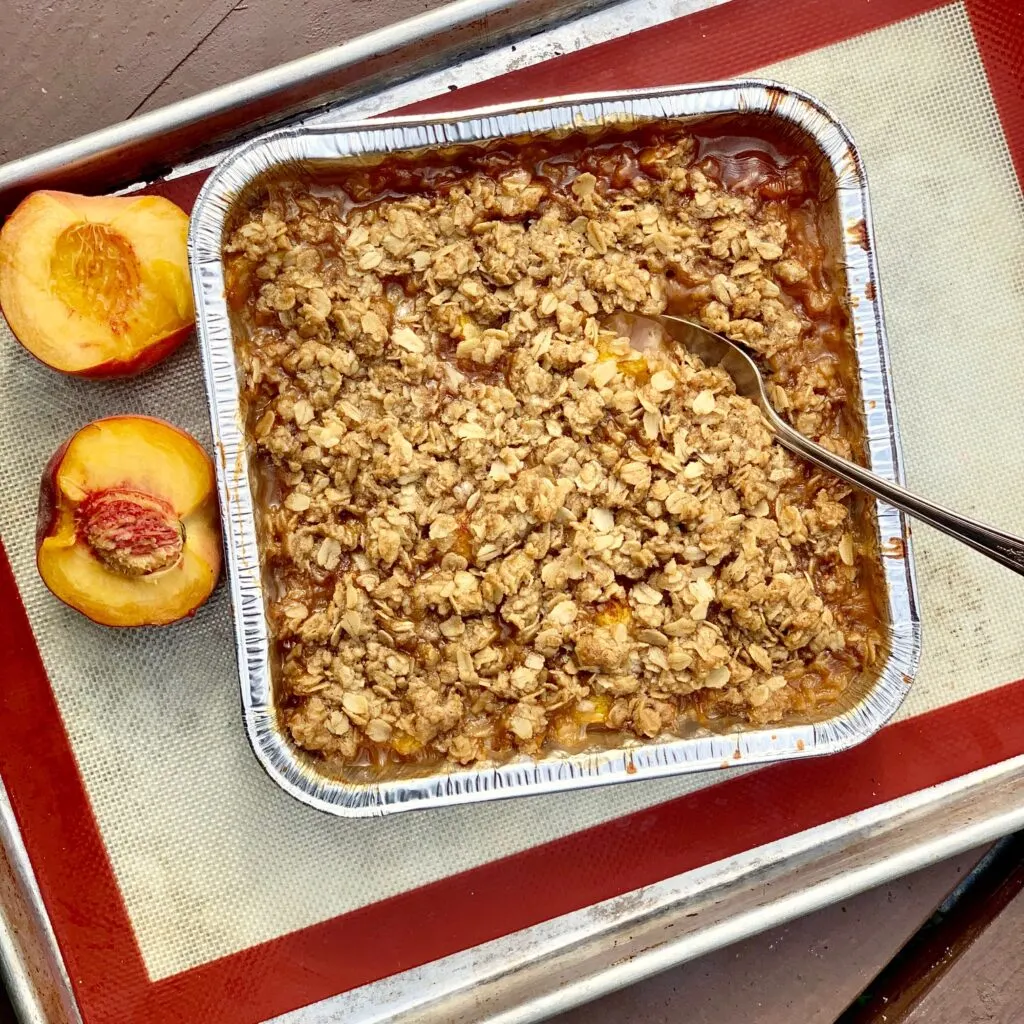 A fresh baked peach crisp on a picnic table