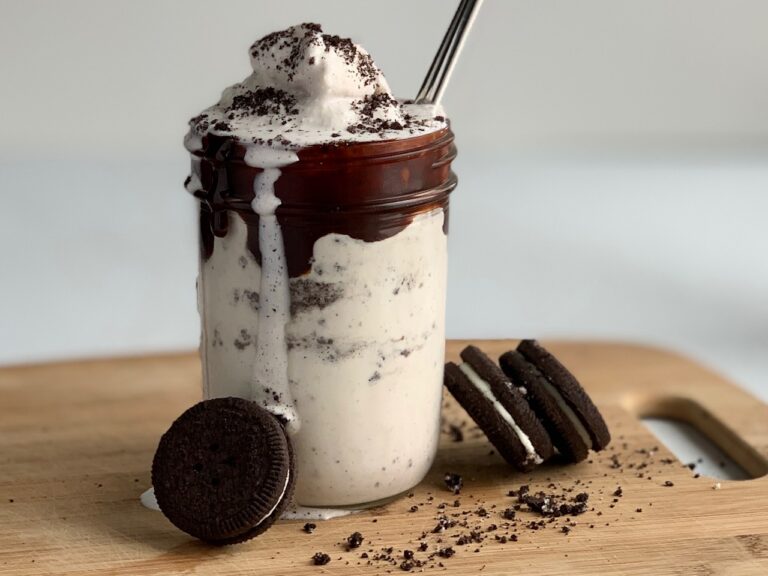 A glass jar filled with a thick and creamy homemade oreo milkshake and oreo cookies on the side. All gluten and dairy free.