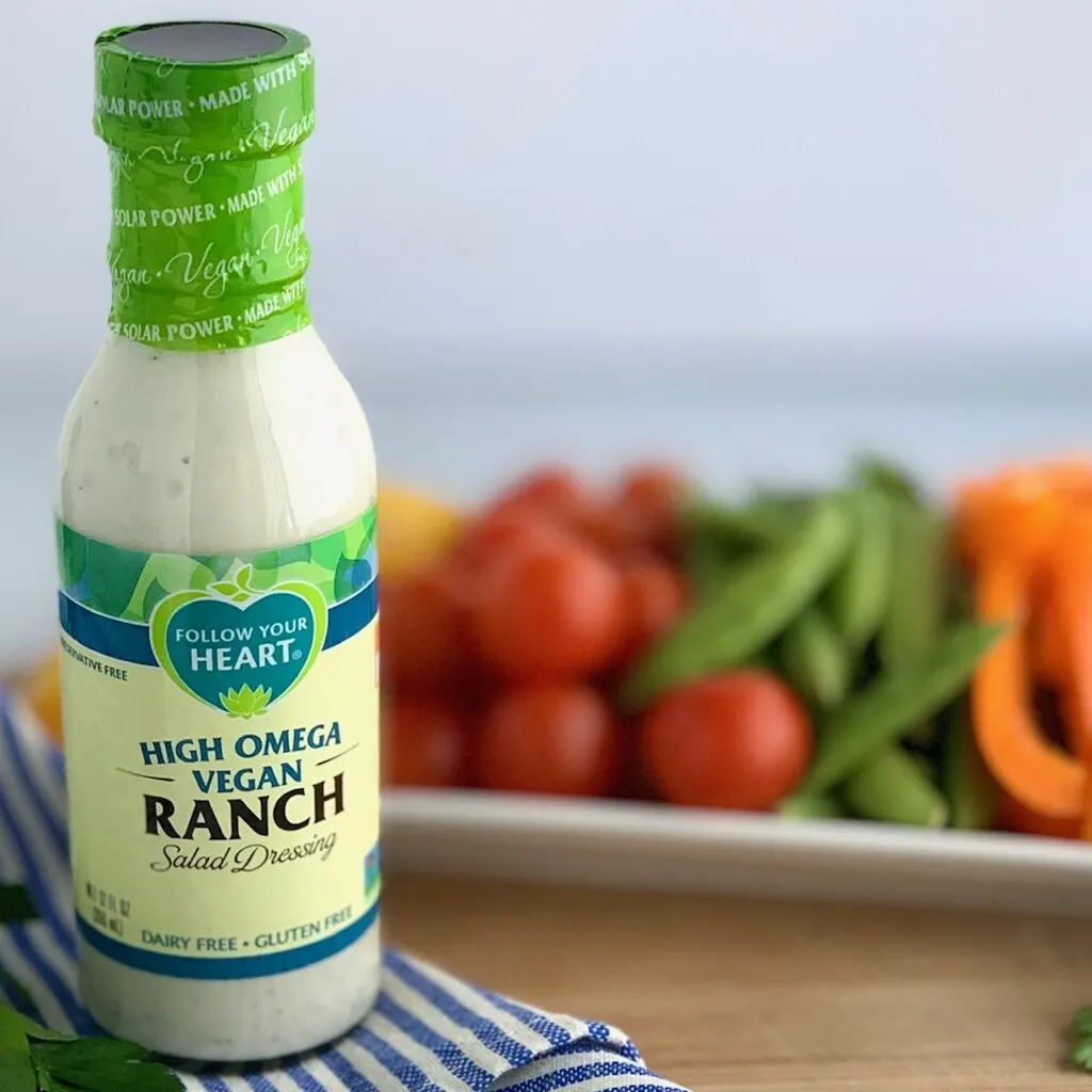 A bottle of Follow Your Heart Ranch dressing next to a platter of yummy vegetables. 