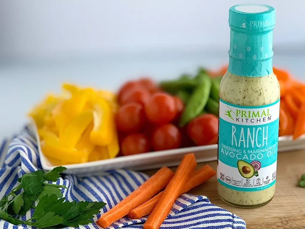 A Primal Kitchen Ranch dressing bottle next to a platter of vegetables. 