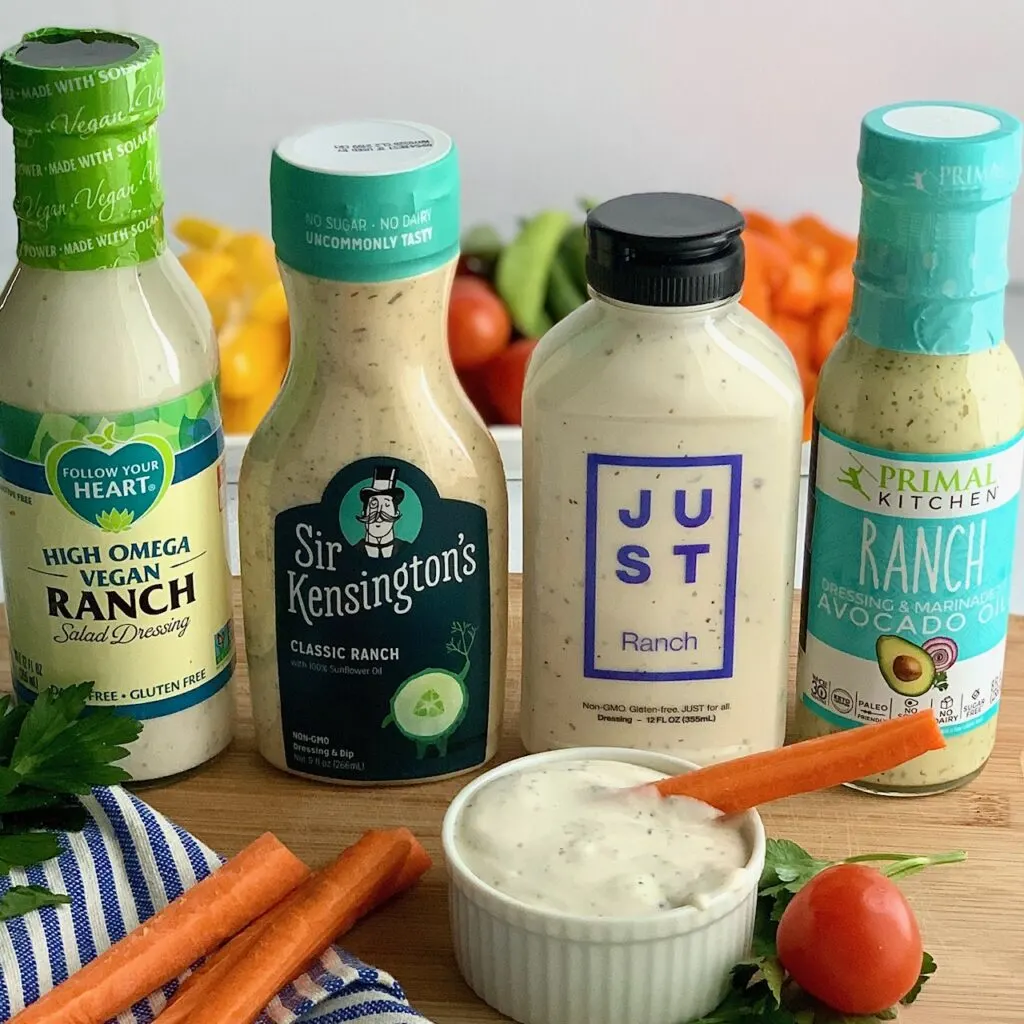 Four dairy free ranch dressings next to a small bowl of ranch dressing with carrots.