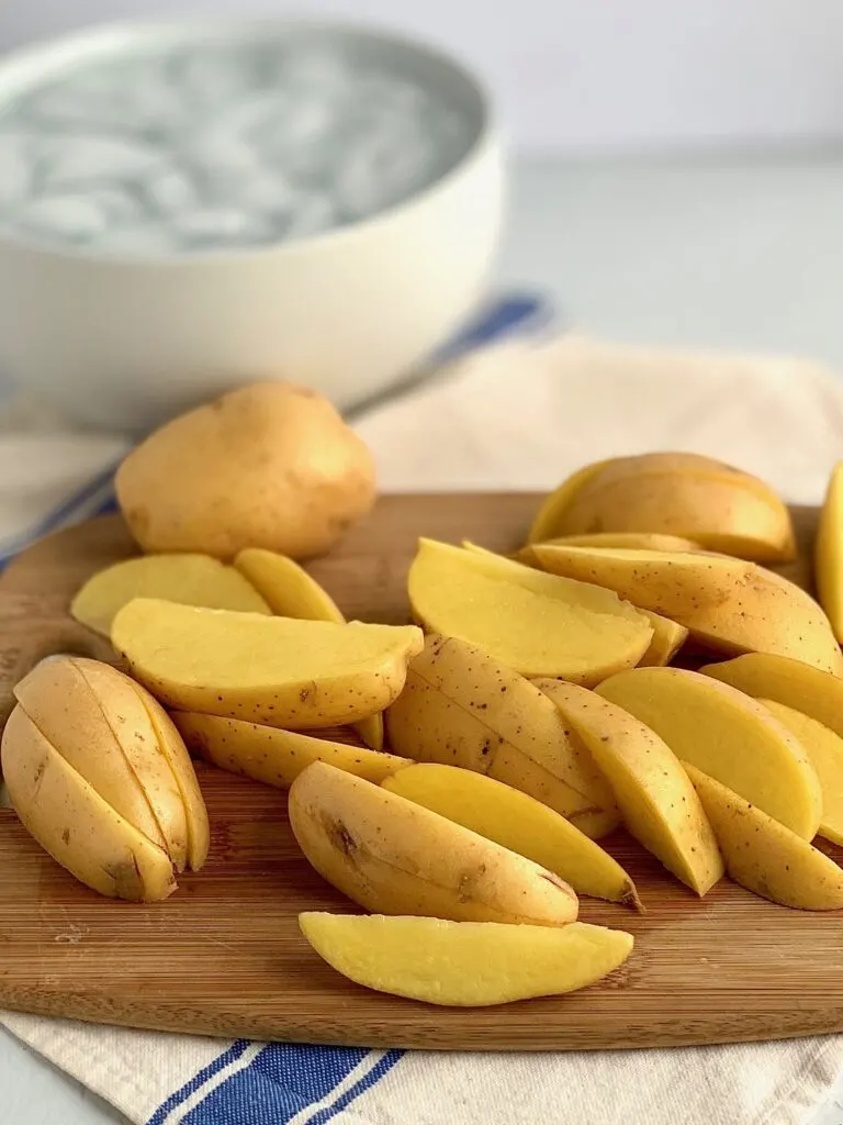 Potato wedges next to a large bowl of ice water