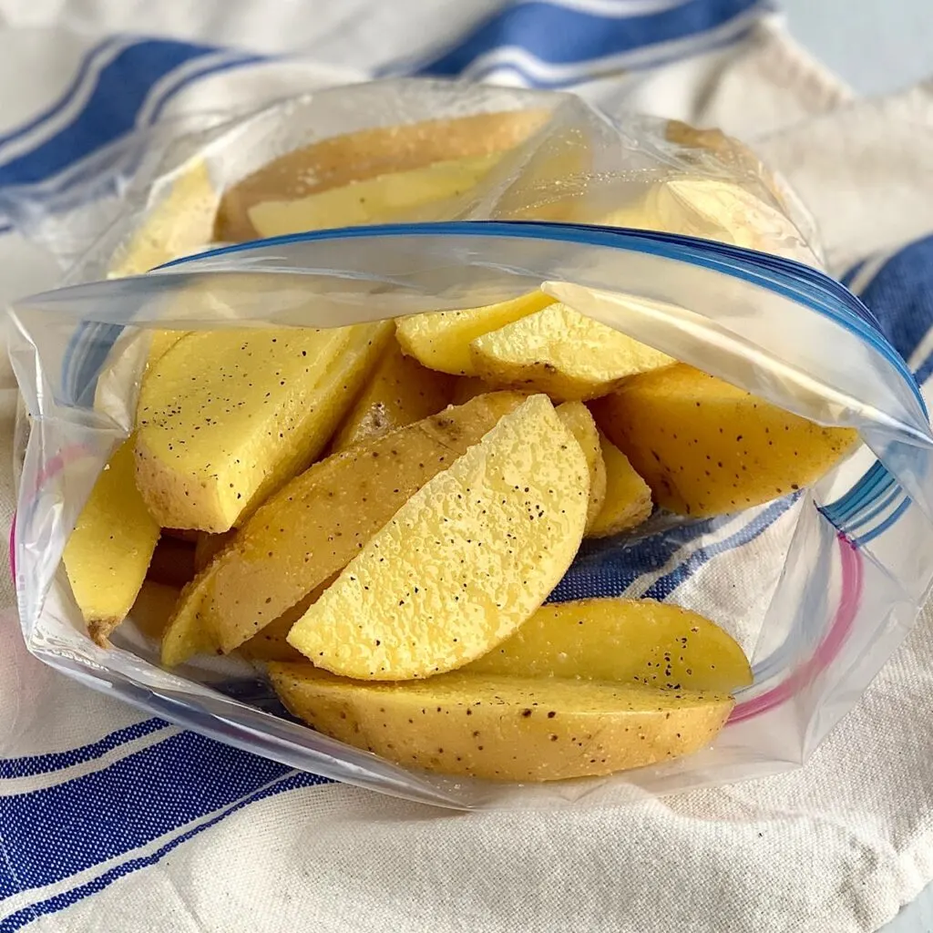 Potato wedges in a Ziploc bag with seasonings and oil