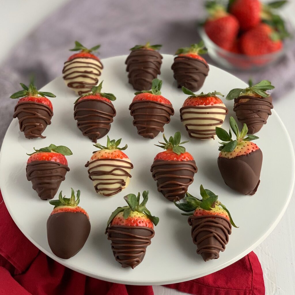 Chocolate covered strawberries on a platter in melted semi sweet, dark chocolate, and white chocolate.