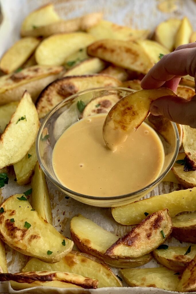 Dipping a baked potato wedge into a bowl of homemade Chick-Fil-A Sauce