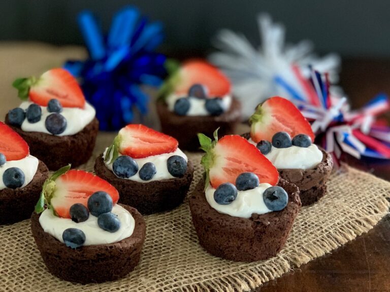 A dinning table full of mini brownie pieces then topped with cocowhip and blueberries and fruit.