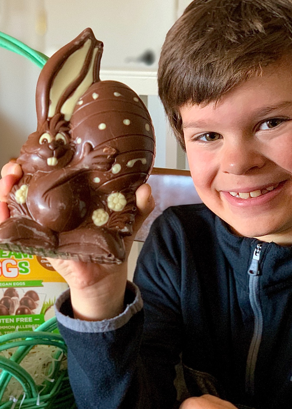 A boy holding a large chocolate bunny.