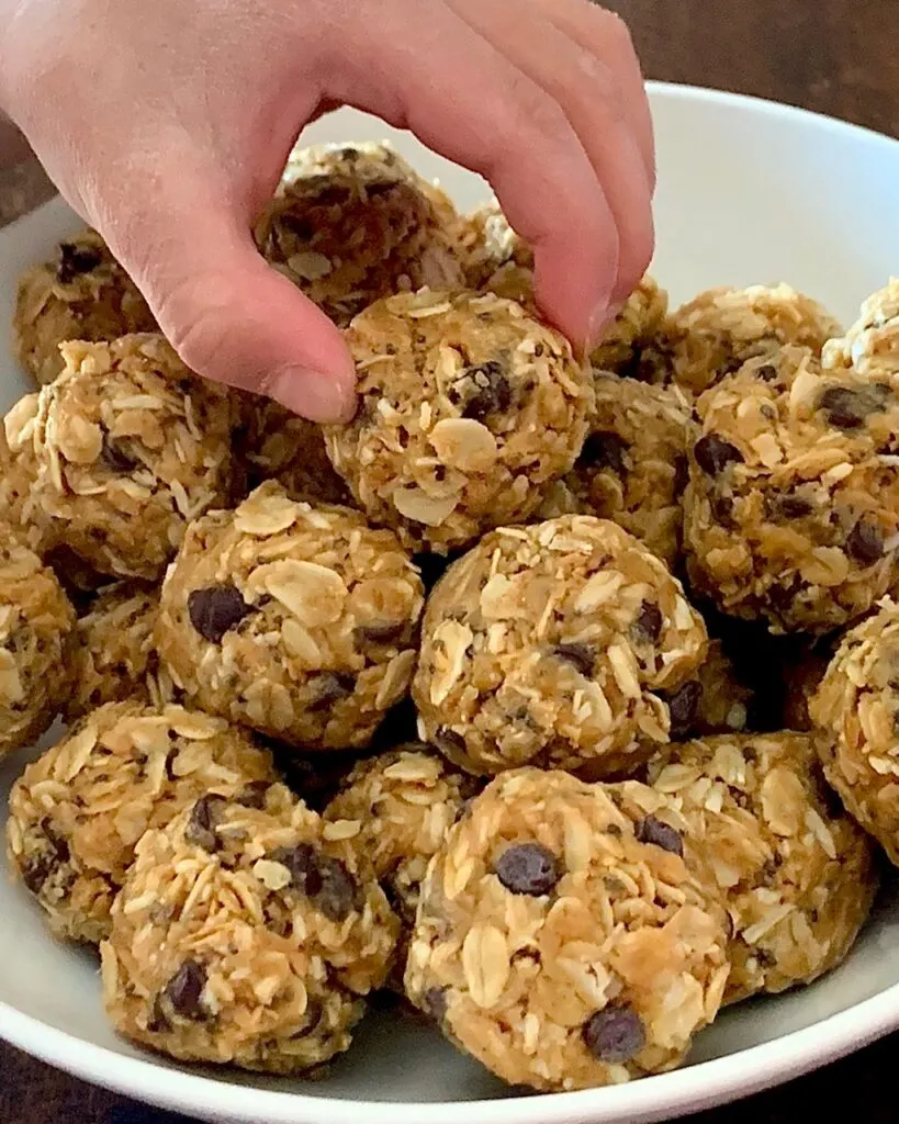 A child reaching for a bowl full of gluten and dairy free energy bites.