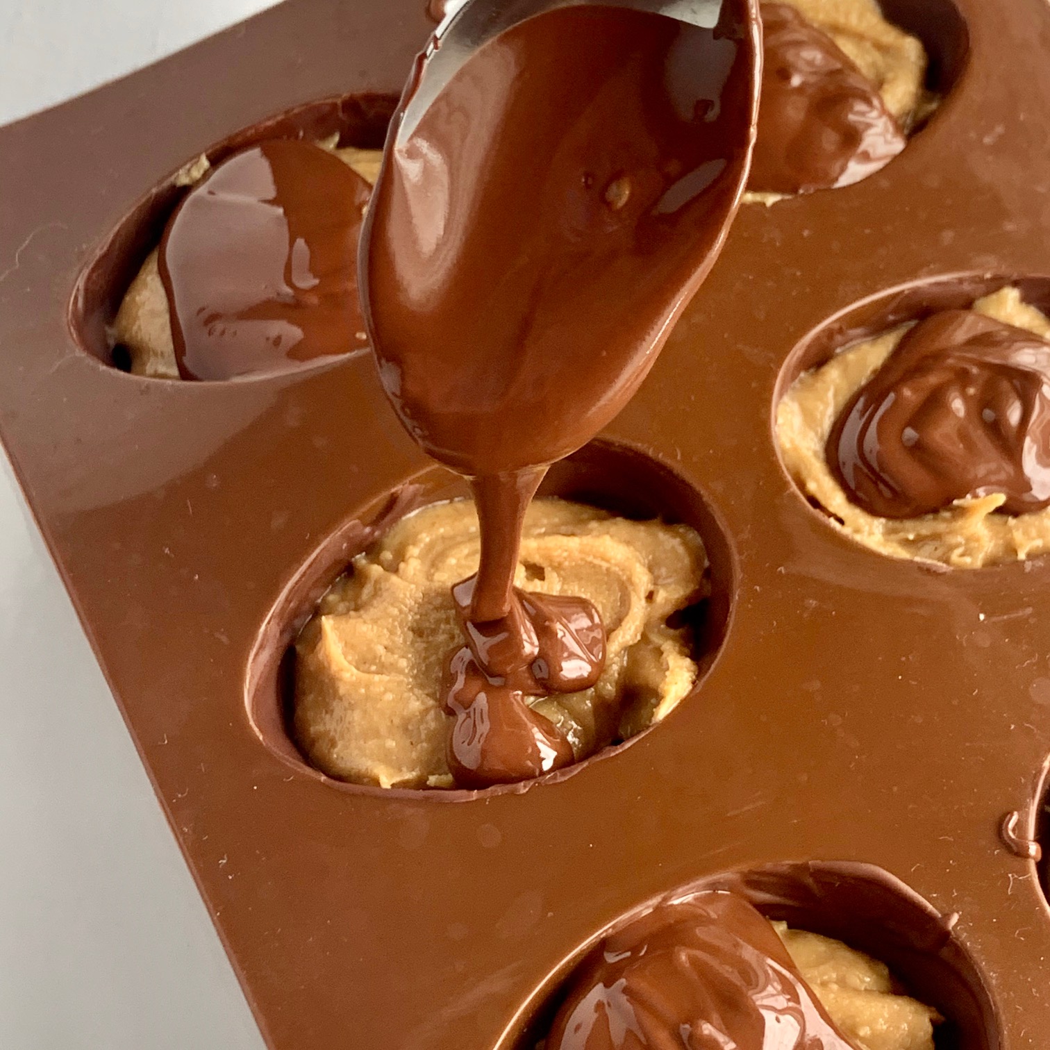 Chocolate being drizzled on top of the peanut butter mixture.