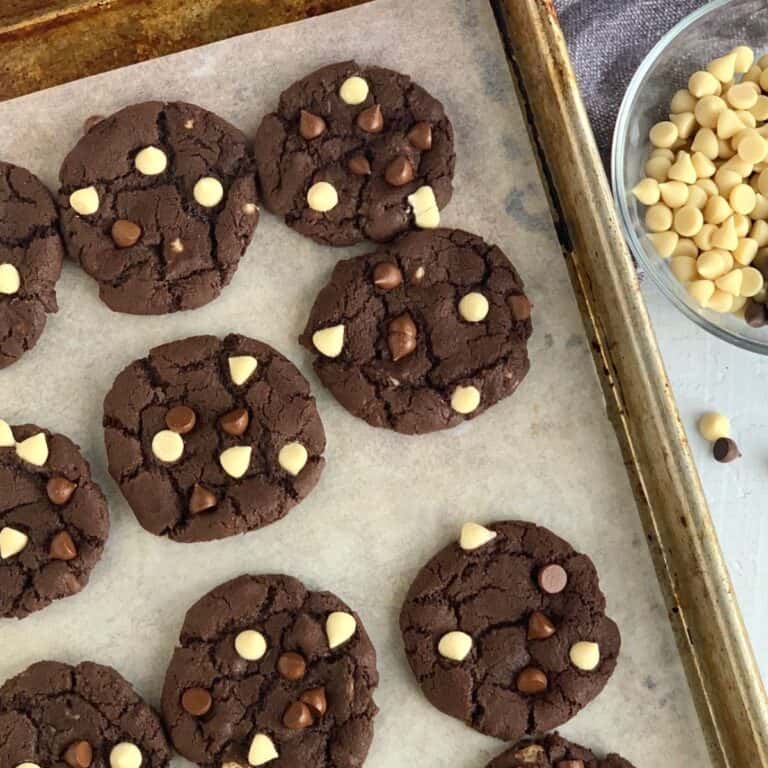 A lined baking tray with a bunch of white chocolate chip cookies.