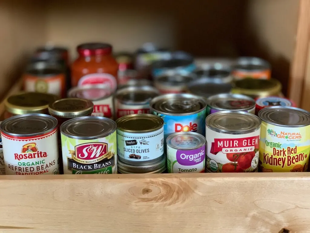 Several canned items in a pantry drawer.