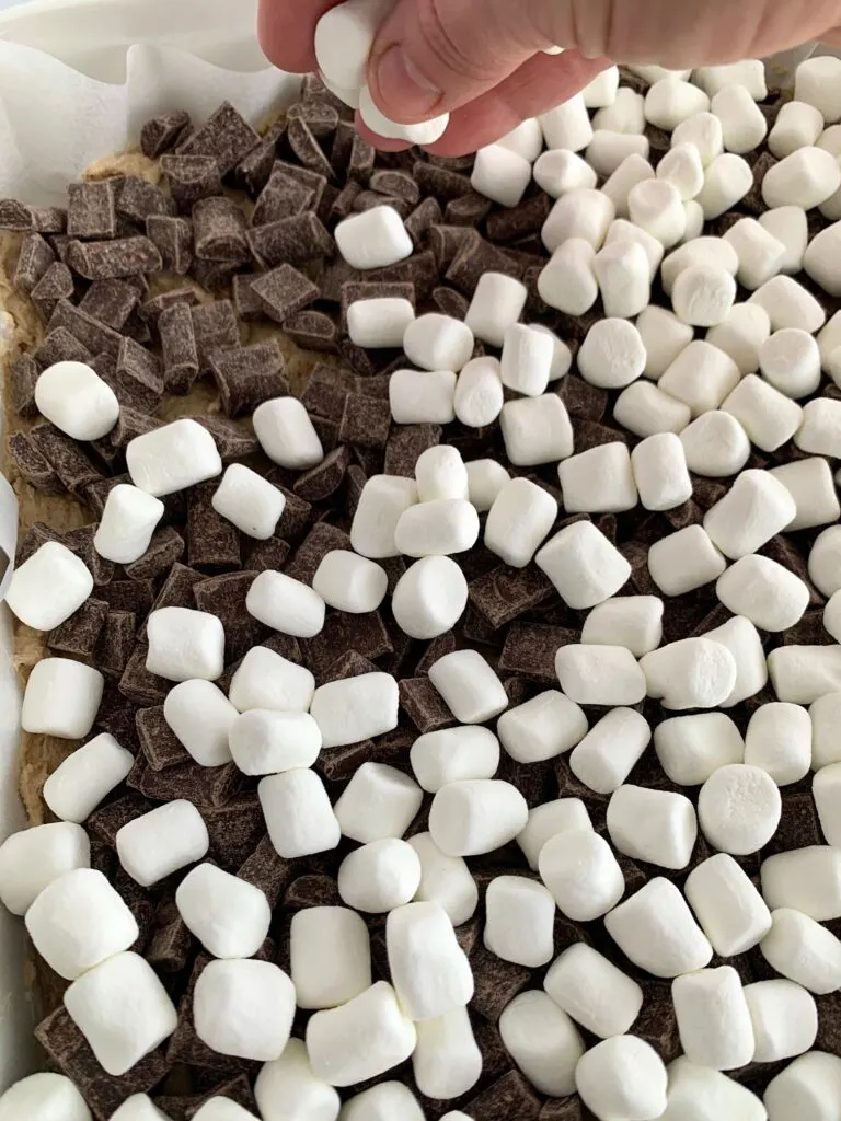 Spreading marshmallows on top of the chocolate chunks. 