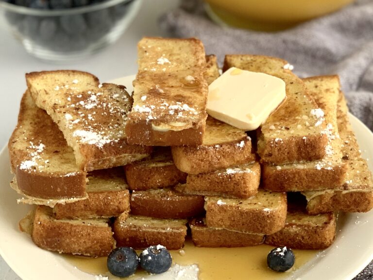 French toast sticks on a serving plate with dairy free butter and powered sugar.