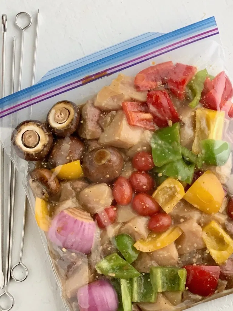 Cut up veggies, steak, and chicken in a Ziploc bag with a shish kabob marinade