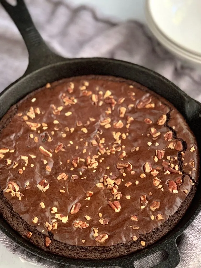 Baked brownie in a skillet with chopped walnuts on top