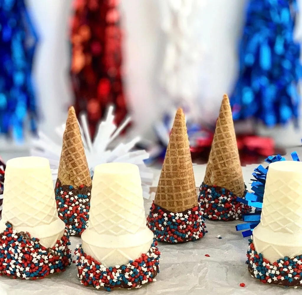 ice cream cones that have been dipped in chocolate and sprinkles added.