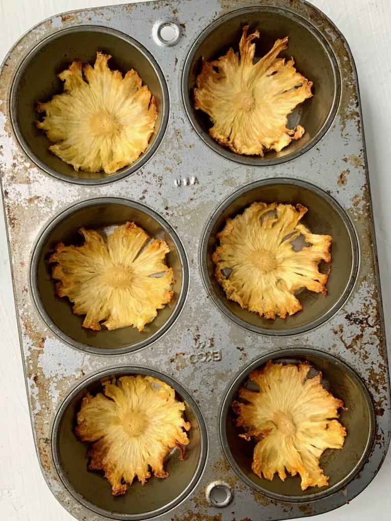 Pineapple slices drying in a muffin tin.