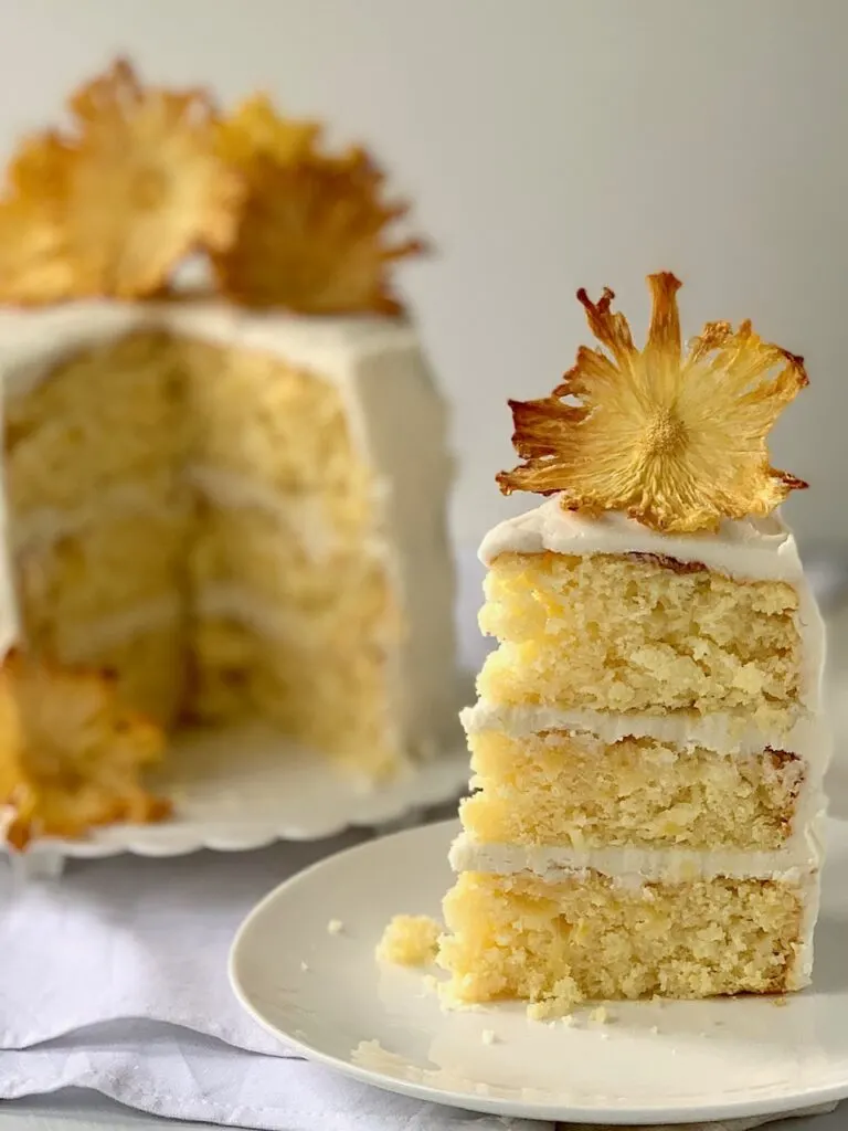 A 3 layer pineapple cake with buttercream frosting and dried pineapple slices that look like flowers