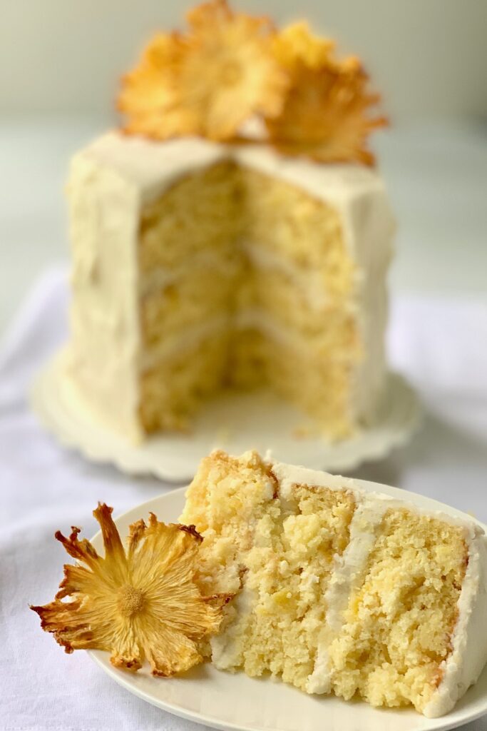 A 3 layer pineapple cake with buttercream frosting and dried pineapple slices that look like flowers