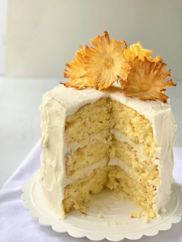 A 3 layer pineapple cake with buttercream frosting and dried pineapple slices that look like flowers