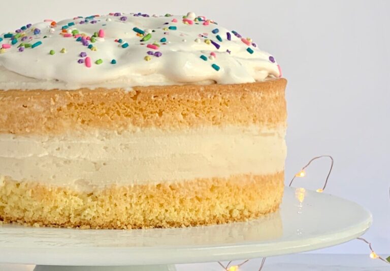 Ice cream sandwiched between a top and bottom layer of yellow cake mix then topped with whipped topping and sprinkles.