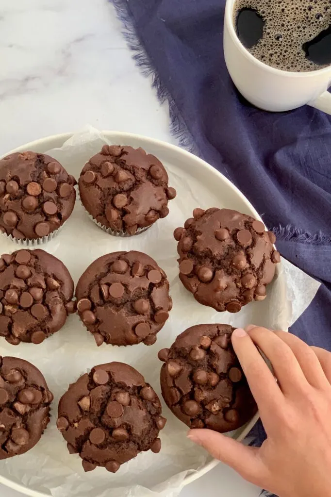 A hand reaching for double chocolate muffins.