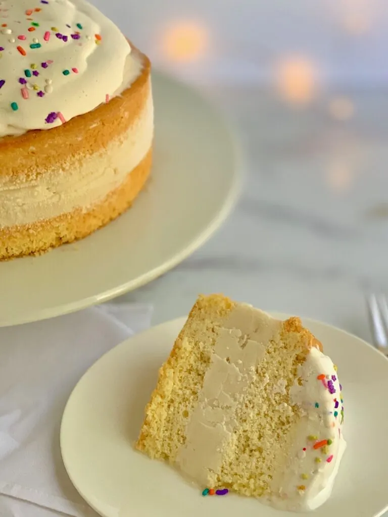 A slice of ice cream cake with whipped topping and sprinkles on it. 