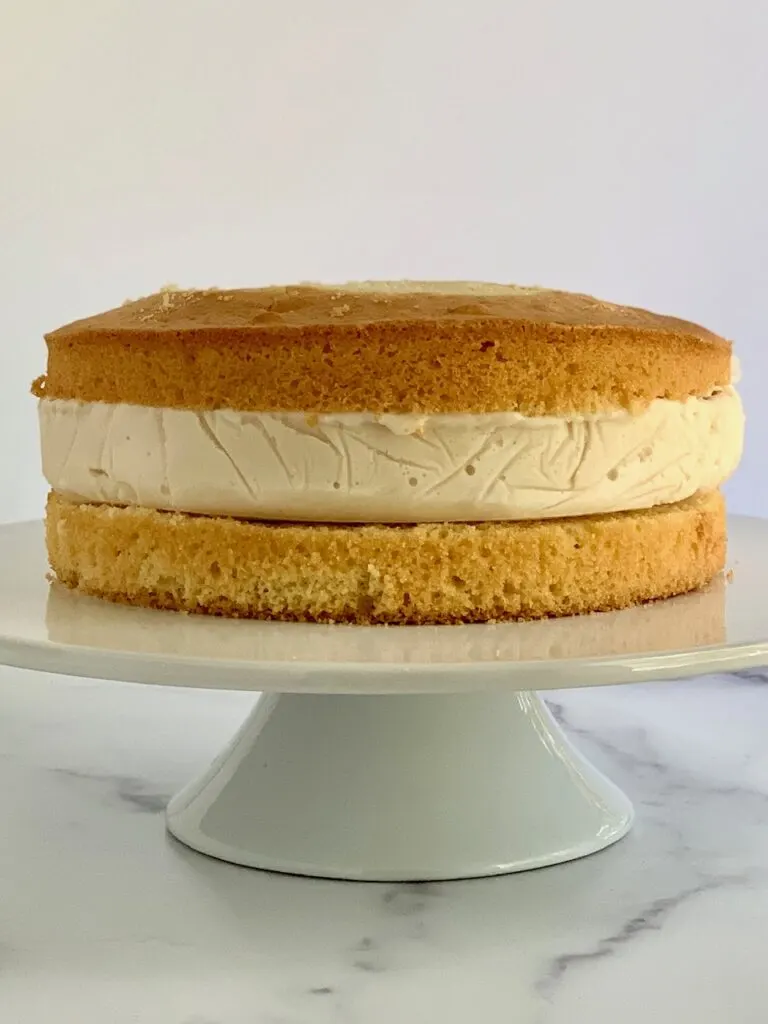 A layer of ice cream between a top and bottom layer of yellow cake before it's decorated. 