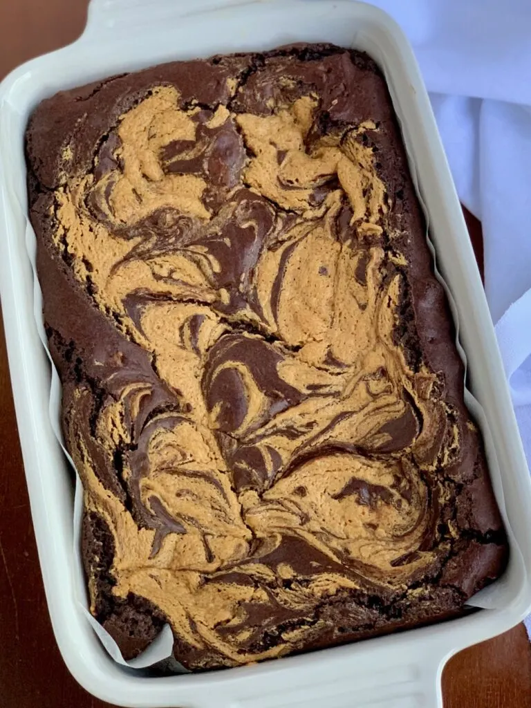 A peanut butter mixture swirled into brownie batter in a baking dish.